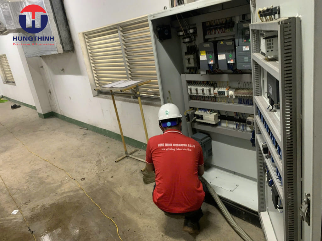 công nhân đang làm Vệ sinh hút bụi cho tủ điện